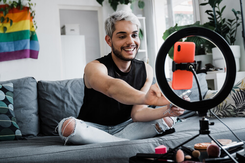 A young man sitting on a couch and recording a video 