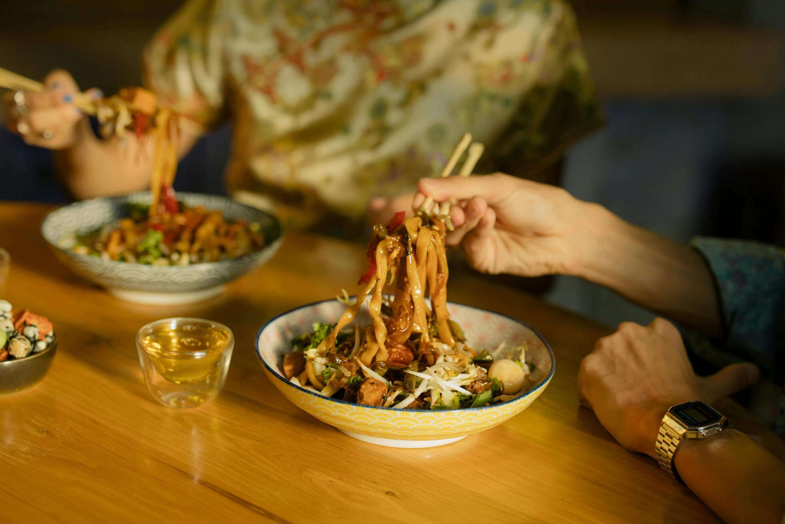 2 people eating Chinese food with chopsticks 