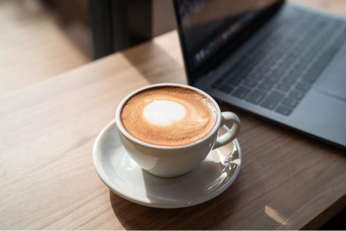 A cup of coffee next to a laptop 